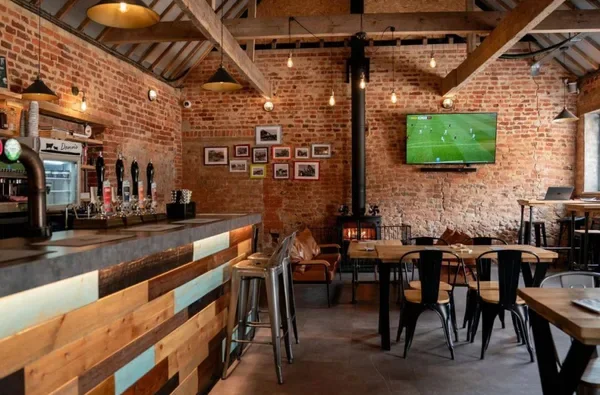 Inside Barsham Brewery Taproom with its wooden bar, exposed brick walls and seating